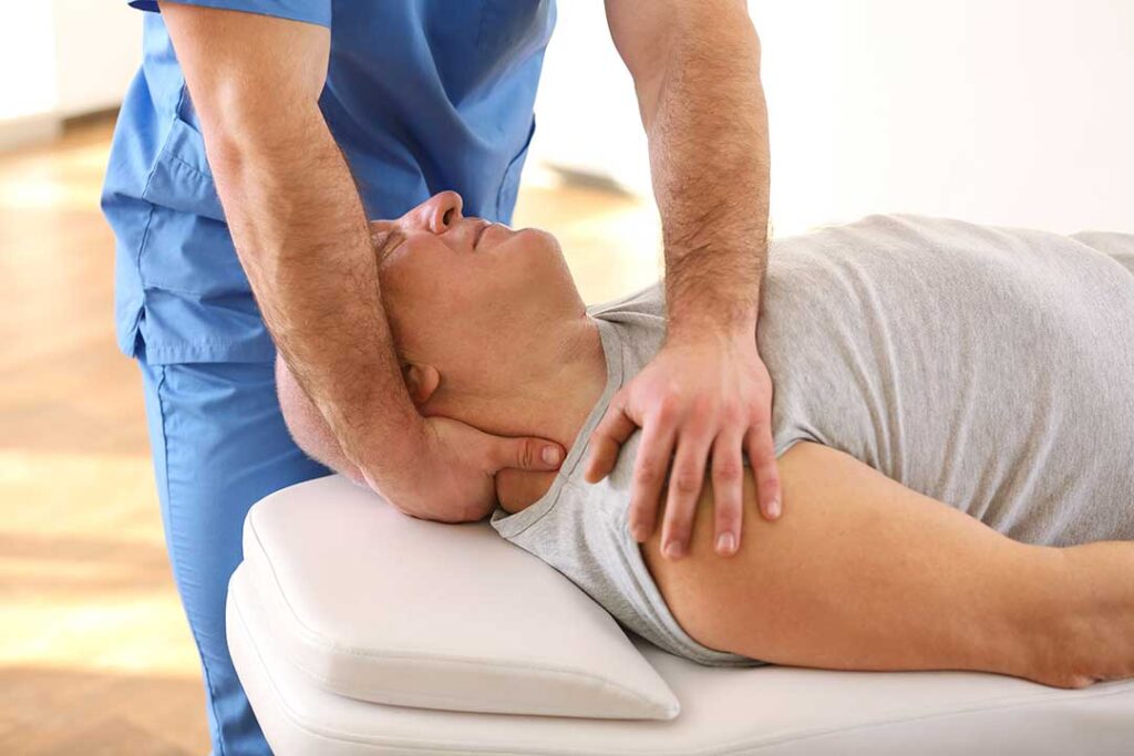 A chiropractor gently adjusts a patient's back in a bright, clean treatment room.